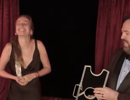 woman in black dress laughs while Matt Donnelly holds arm chopper