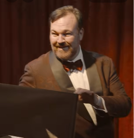 Matt Donnelly the Mind Noodler in a tux onstage rolling out tinfoil to blindfold himself